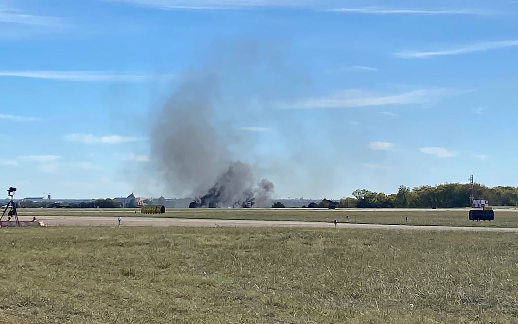 This image obtained from the Twitter account @GollyItsMollie, shows smoke rising from the crash after two planes collided mid-air during the Wings Over Dallas Airshow at Dallas Executive Airport, in Dallas, Texas, on 12 November 12, 2022. Two World War II-era airplanes collided at the air show in Dallas, US aviation authorities confirmed. It was not immediately clear how many people were in the two craft, a Boeing B-17 Flying Fortress and a smaller Bell P-63 Kingcobra, the Federal Aviation Administration said. Nor was it clear whether anyone survived the early afternoon crash, which occurred during the Wings Over Dallas Airshow at Dallas Executive Airport.