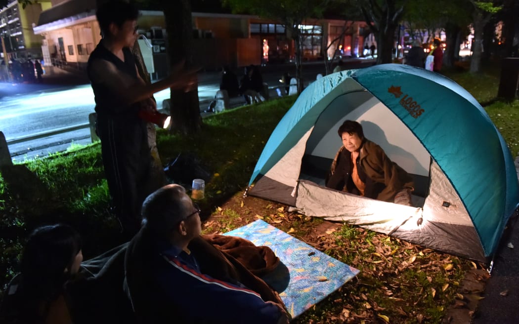 Evactuated residents wait at a park in Higashi-ku in Kumamoto City.