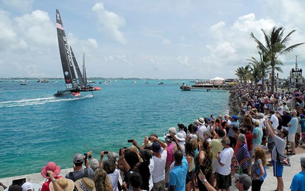 America's Cup defender sails by the crowds on shore at Bermuda.
