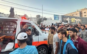 People gather around an ambulance damaged in a reported Israeli strike in front of Al-Shifa hospital in Gaza City on November 3, 2023, as battles between Israel and the Palestinian Hamas movement continue. According to the head of the Hamas government's press service, the strike targeted "an ambulance convoy which was preparing to transport wounded people from Al-Shifa hospital" to the border with Egypt. Several people were killed and injured in the strike. (Photo by MOMEN AL-HALABI / AFP)