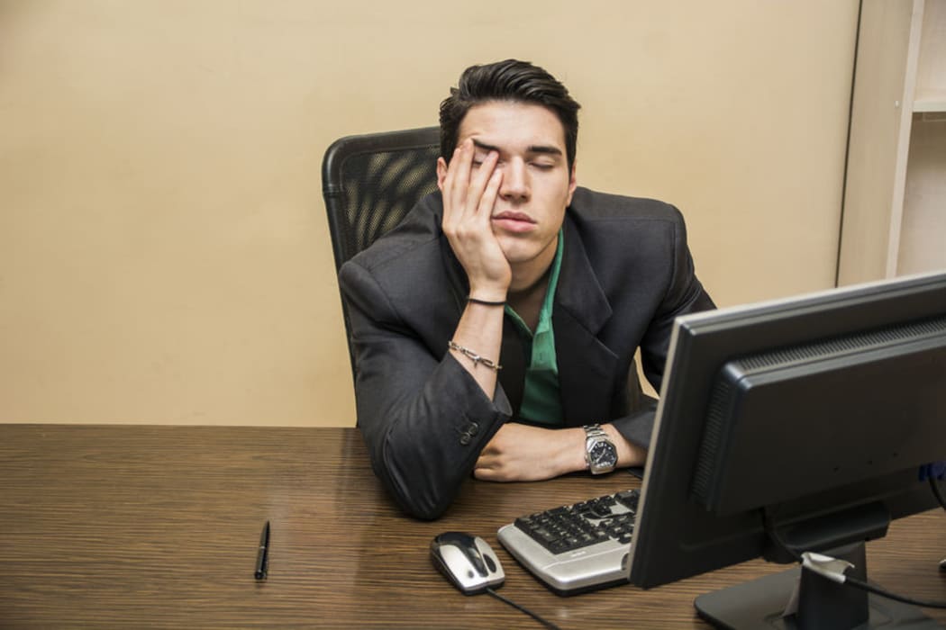 Man with head in hands in front of computer