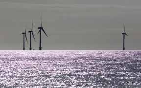 Offshore wind farm wind turbines silhouette. Focus on sea horizon. Picture taken shortly after sunrise. Crisp black sihouetted windmills or turbines in profile. Clean energy production North sea UK.