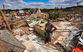 Nereu Sabadini sits on the debris of his house destroyed by a tornado with winds of up to 250 km/h that hit the city of Rio Bonito do Iguaçu, in Paraná state, Brazil, on November 8, 2025.