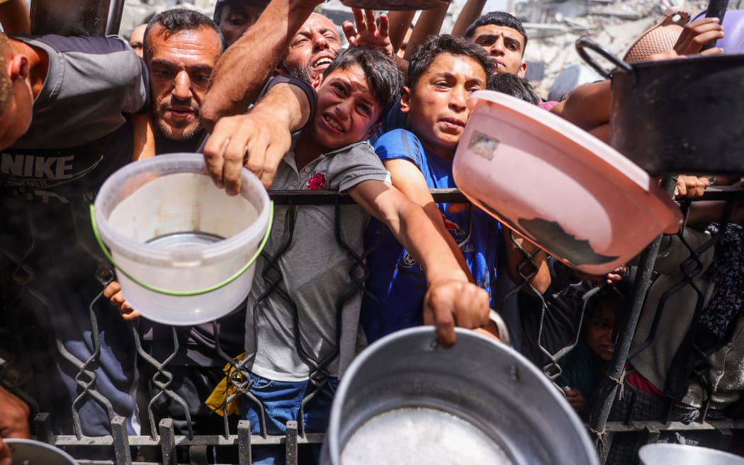 Palestinians shove to get a portion of cooked food from a charity kitchen in Jabalia in the northern Gaza Strip on 17 May, 2025. The humanitarian crisis in the besieged Gaza Strip has worsened significantly since Israel blocked all aid from entering the territory on March 2, days before resuming its military offensive following a brief ceasefire.