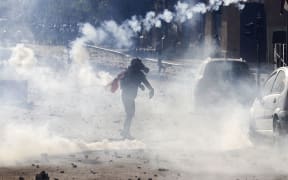 A Lebanese demonstrator throws a tear-gas canister back at security forces during clashes in downtown Beirut on August 8, 2020, following a demonstration against a political leadership