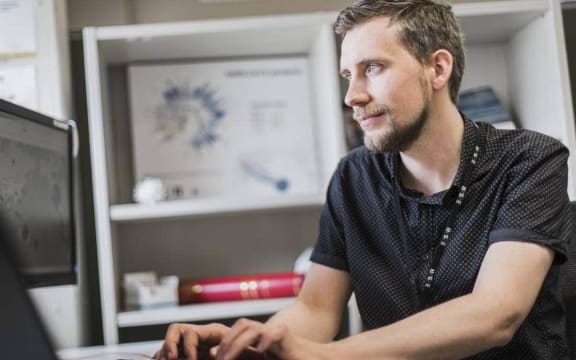 Joep is sitting at a computer typing.