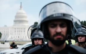 Police in riot gear stand in front of the US Capitol during the Justice for J6 rally.