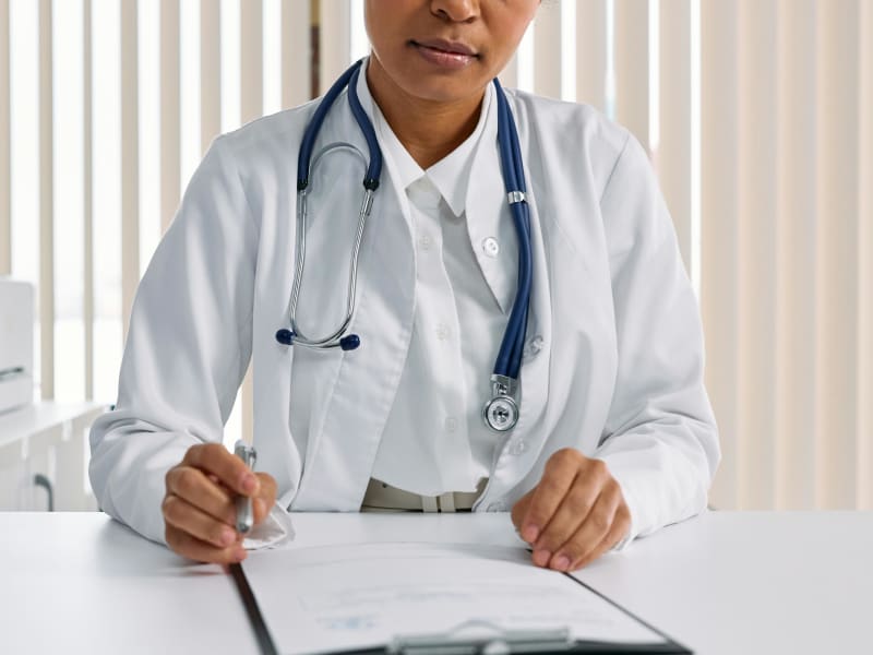A woman in a white doctot's coat with a stethescope around her neck.