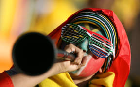 A football fan blows a vuvuzela.