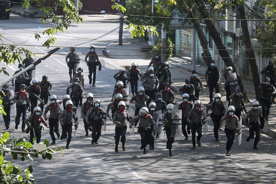 Police run towards protesters to disperse a demonstration being held against the military coup in Yangon on 3 March