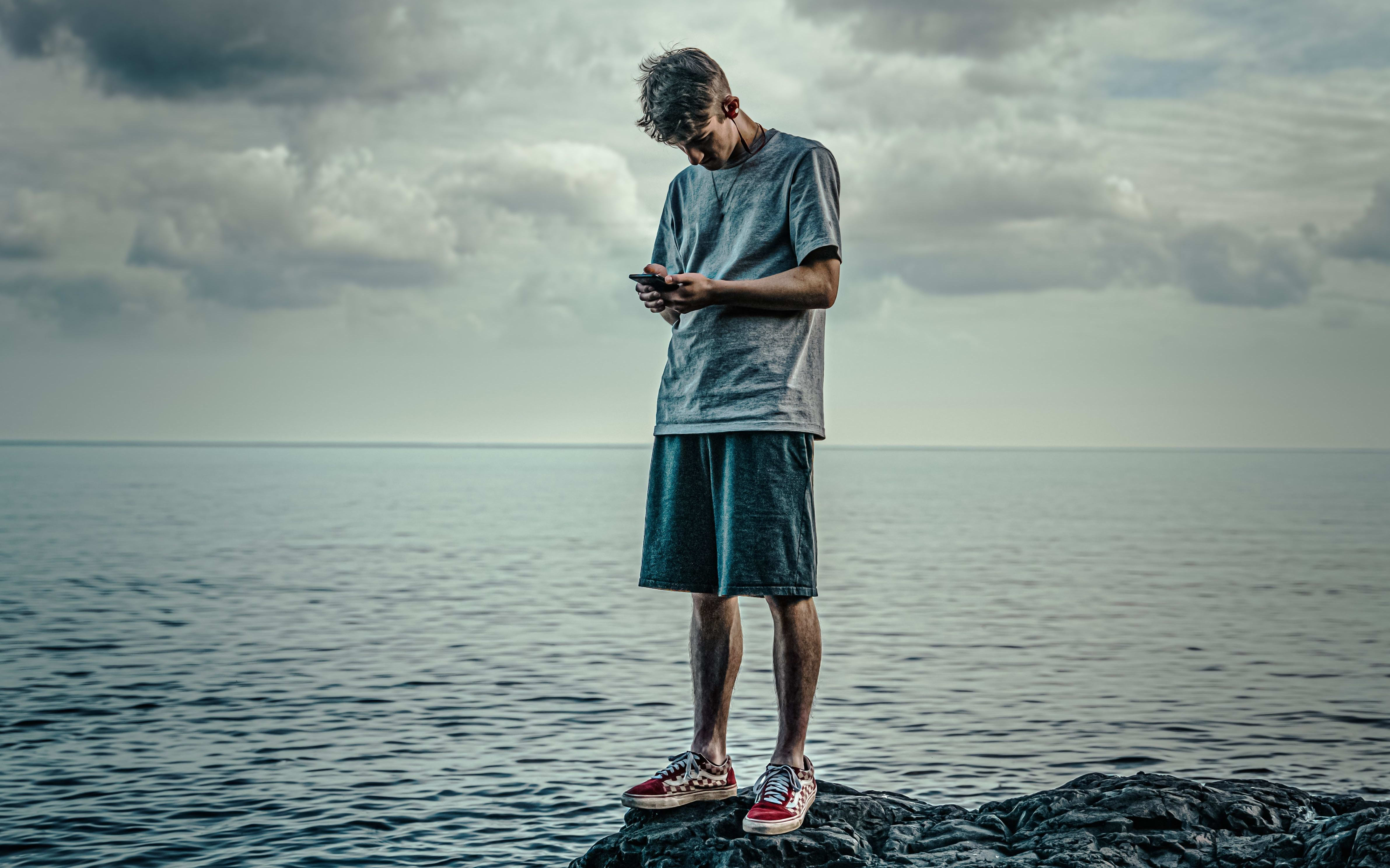 young man on phone by the sea