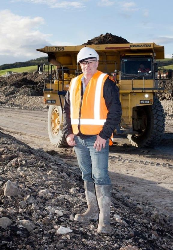 Bathurst Chief Executive stands in hard hat and gumboots near heavy truck and coal.