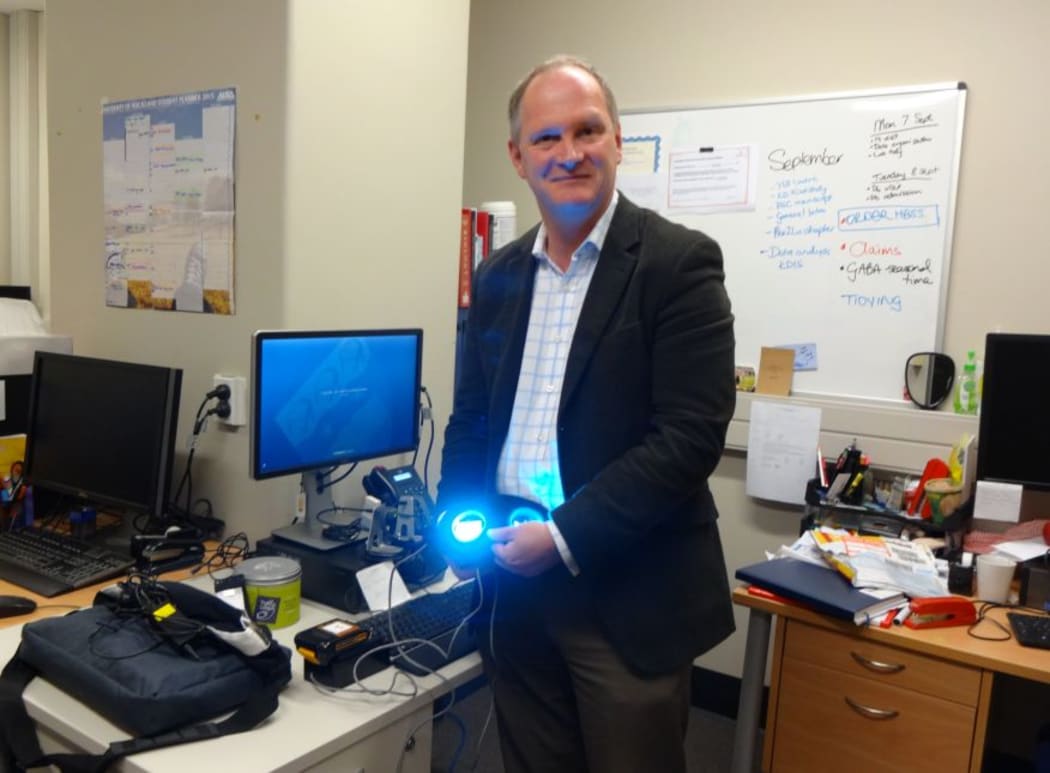 Guy Warman with a pair of light-producing goggles, which the team uses to give light therapy to patients during surgery.