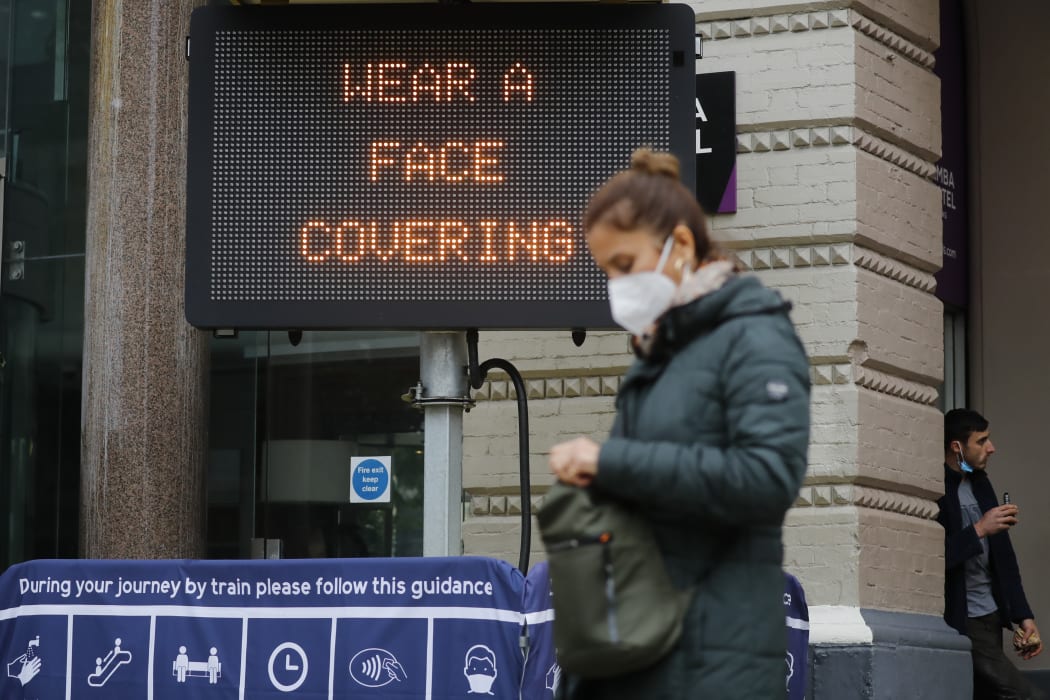 A pedestrian walks past a sign displaying a message to wear a face covering, outside Charing Cross station in central London on 14 October 2020.