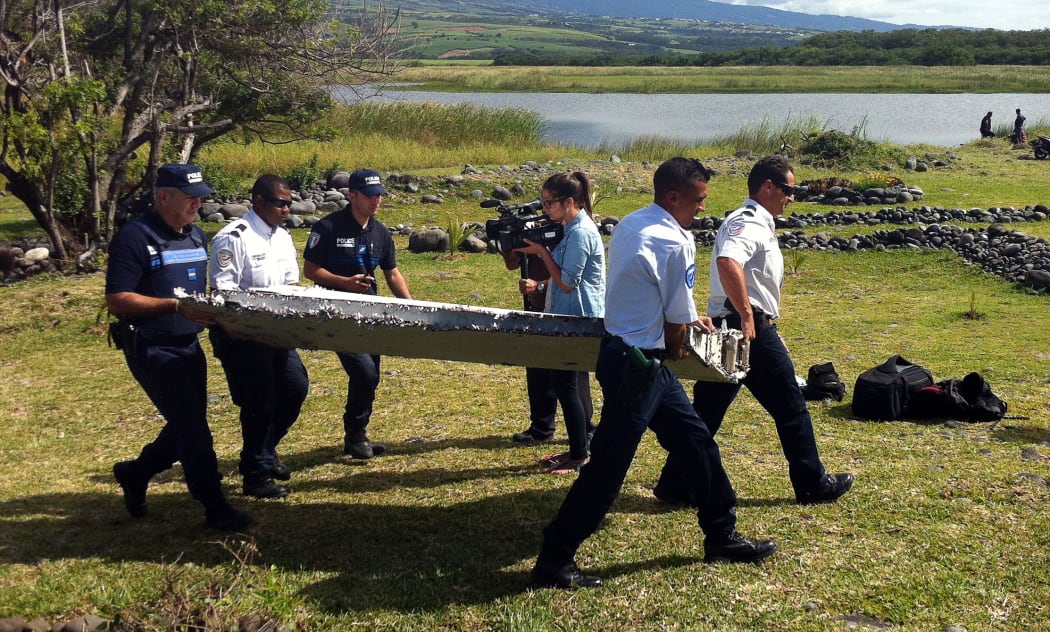 Police carry debris from an aircraft found on the Indian Ocean island of La Reunion.