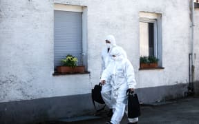 Members of the crime scene unit walking past the house of the accused couple in Hoexter, Germany.