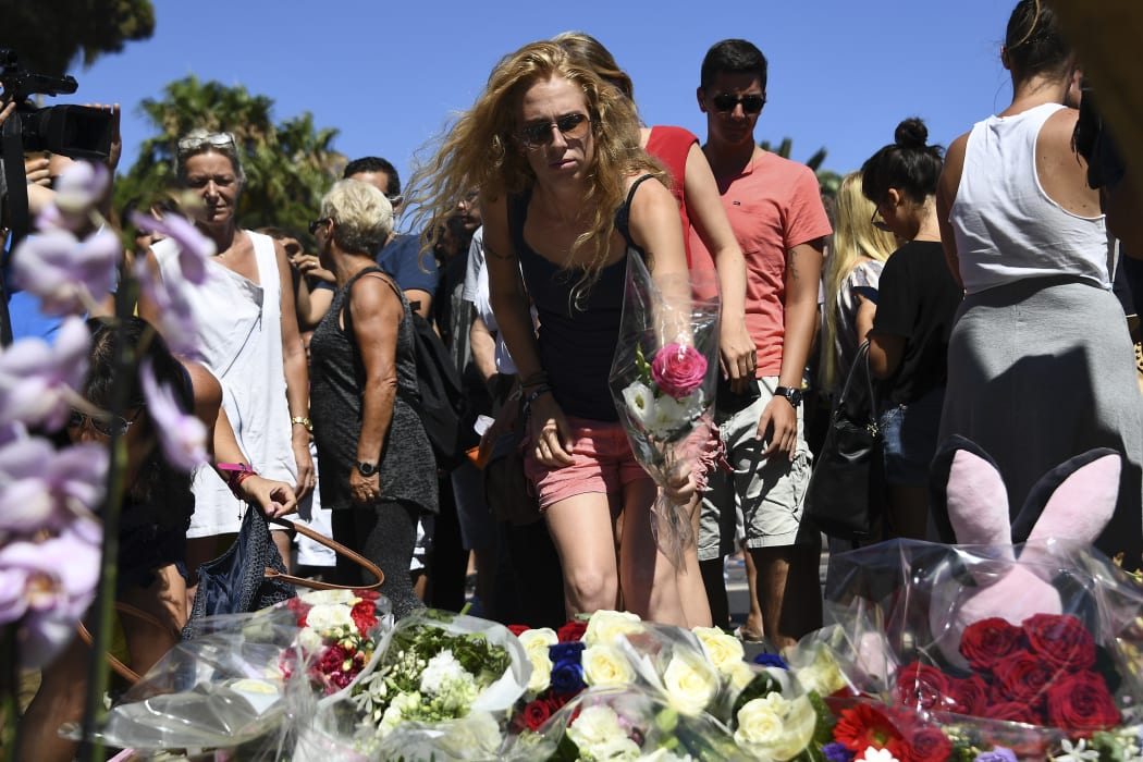 A woman lays a flower in the street of Nice to pay tribute to the victims of the Bastille Day attack.