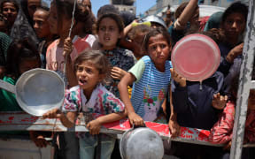 Palestinian children wait with others for food at a distribution point in Gaza City, on June 3, 2025. Israel faces growing condemnation over the humanitarian crisis in the war-ravaged Gaza Strip, where the United Nations warns the entire population faces the risk of famine after no aid is allowed to enter for more than two months. (Photo by Majdi Fathi/NurPhoto) (Photo by MAJDI FATHI / NurPhoto via AFP)