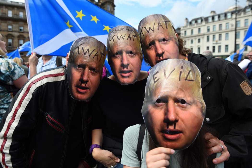 Demonstrators wearing defaced masks depicting Britain's Prime Minister Boris Johnson join a protest against the British government's move to suspend parliament.