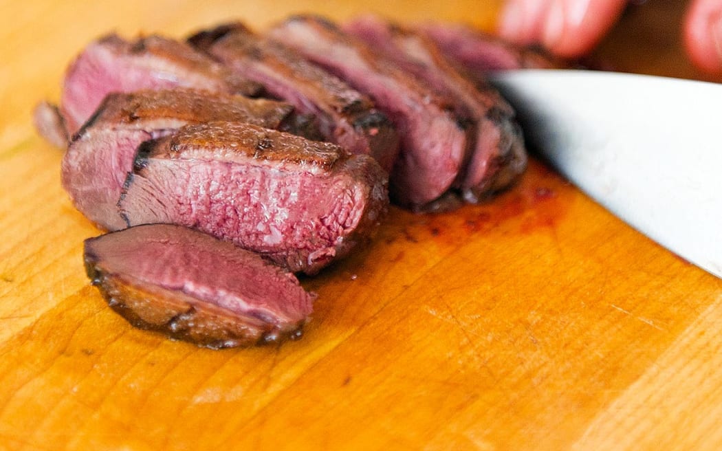 A person slices roast duck breast