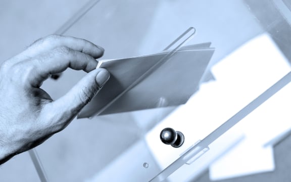 Hand putting a blank ballot inside the box, elections concept.