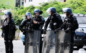 French Gendarmerie stand with their shields at the entrance of the Vallee-du-Tir district, in Noumea on May 14, 2024, amid protests linked to a debate on a constitutional bill aimed at enlarging the electorate for upcoming elections of the overseas French territory of New Caledonia.