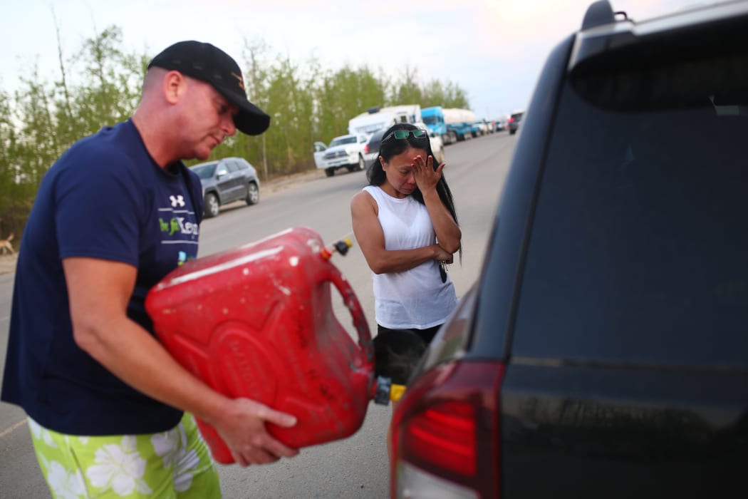 Marilou Wood fights back tears as husband Jim Wood fills up his car with gas after fleeing forest fires in Fort McMurray.
