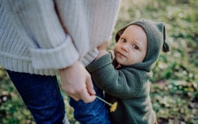 A mother holding hands of her baby son when walking in nature, baby's first steps concept.