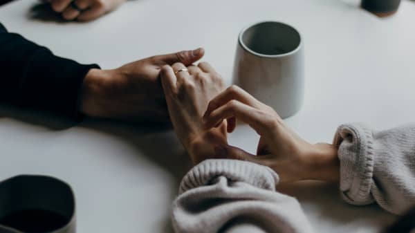 Couple having coffee and holding hands at table.