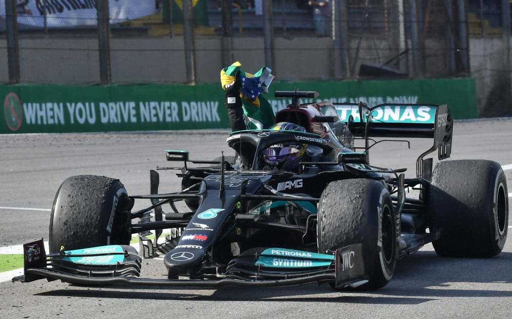 Mercedes' British driver Lewis Hamilton celebrates with a Brazilian flag after winning Brazil's Formula One Sao Paulo Grand Prix at the Autodromo Jose Carlos Pace, or Interlagos racetrack, in Sao Paulo, on November 14, 2021.