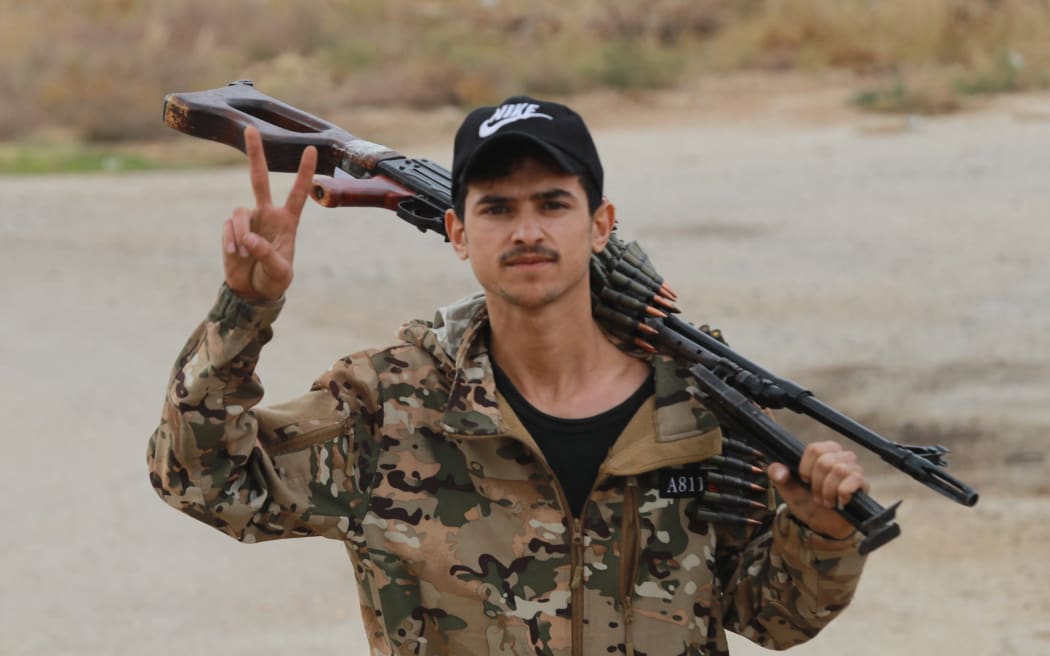 A Syrian Kurdish fighter flashes the V-sign for victory as local gunmen control the area around Qamishli's airport in northeastern Syria on December 8, 2024, following the fall of the capital Damascus to anti-government fighters. - Islamist-led rebels declared that they have taken Damascus in a lightning offensive on December 8, sending President Bashar al-Assad fleeing and ending five decades of Baath rule in Syria. (Photo by Delil SOULEIMAN / AFP)