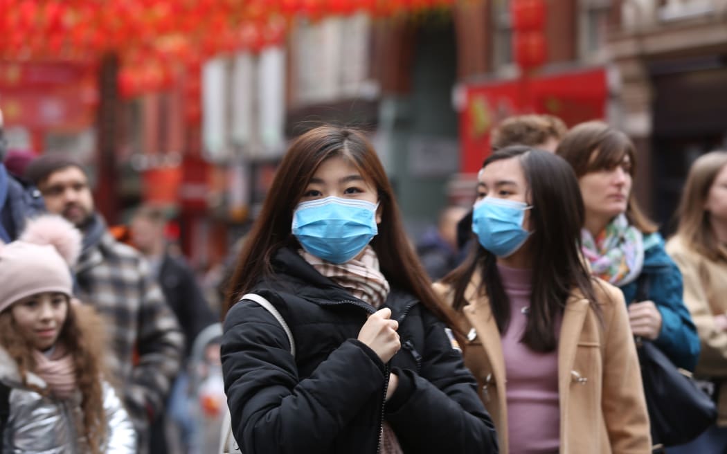 Women wear respirator masks during Chinese New Year Celebration in Chinatown in London, England on January 26, 2020.