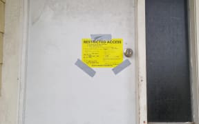 A yellow stickered Māngere house stating residents are only allowed short term entry to the building which has been damaged.