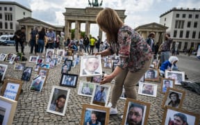 Activists and relatives of Syrians suspected of being detained or missing pose with their portraits during a demonstration in front of Berlin's Brandenburg gate on 7 May, 2022.