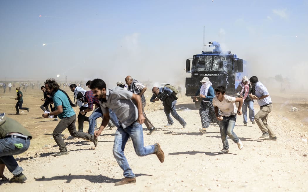 Kurdish protestors clash with Turkish soldiers near the Syrian border after it was temporarily closed by Turkish authorities