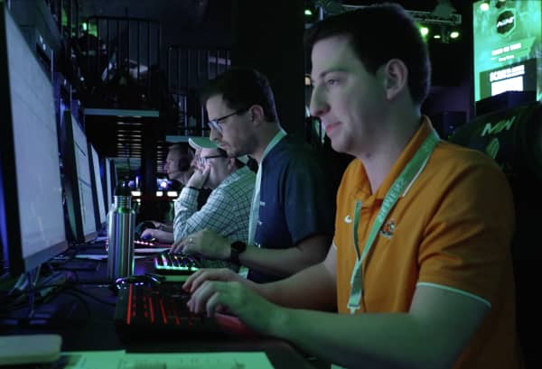 A line of men stare at screens and type on keyboards.