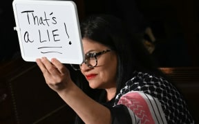 US Democrat Representative Rashida Tlaib (MI) holds up a white board reading "That's a lie" as US President Donald Trump speaks during an address to a joint session of Congress, on 4 March, 2025.