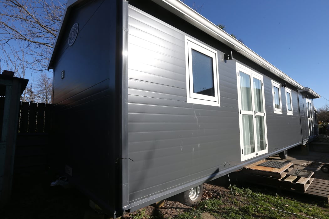 A tiny house on wheels in the backyard of a Renwick house,