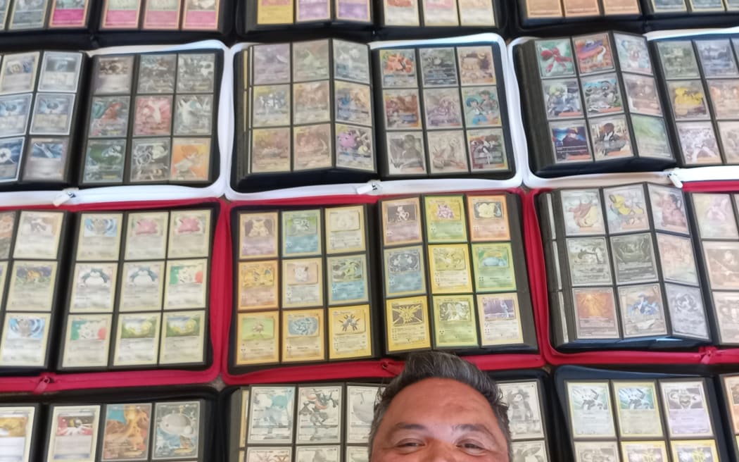 Photo of trading cards collections with a man's half head in a selfie.
