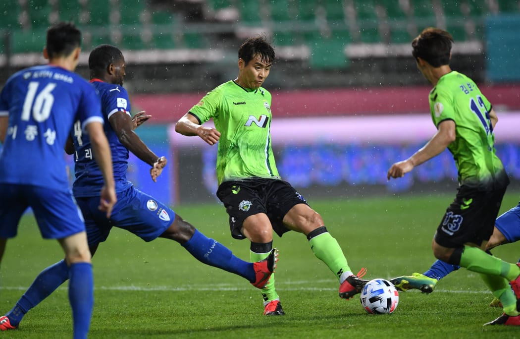 Jeonbuk Hyundai Motors' Lee Dong-gook (C) dribbles the ball against Suwon Samsung Bluewings during the opening game of South Korea's K-League football match at Jeonju World Cup Stadium in Jeonju on May 8, 2020.