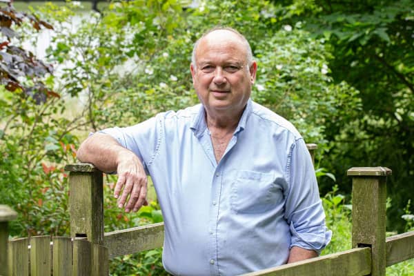 Louis de Bernières leaning on a wooden gate