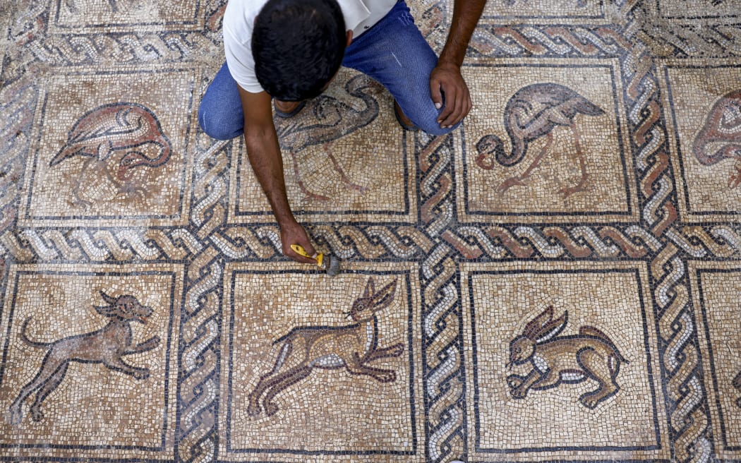 A man uses a brush to uncover Byzantine mosaics dating from the fifth to seventh centuries. They were found less than a km from the often tense border with Israel, and are in amazing condition, said French archaeologist Rene Elter.