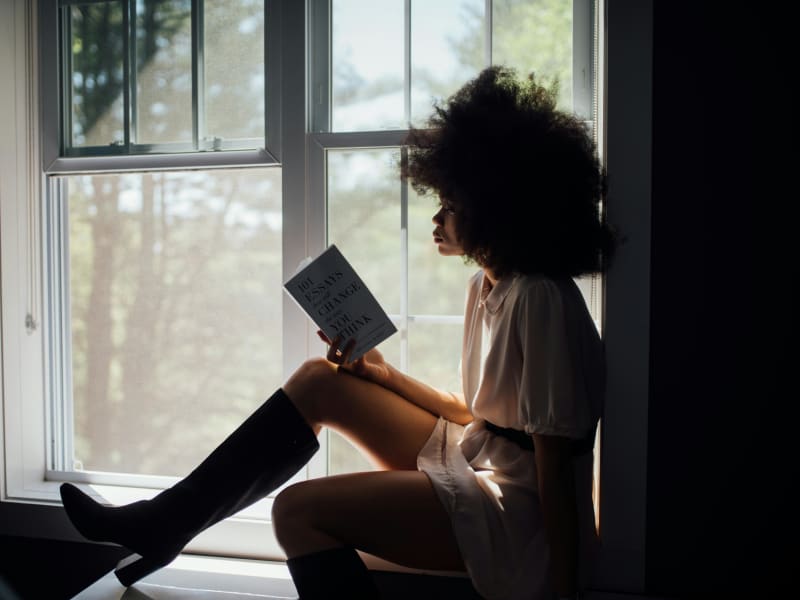 A woman reads a book in a windowsill