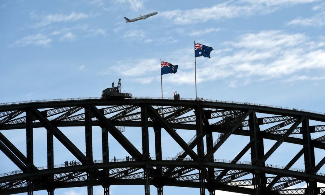 An American Airlines Boeing 777 aircraft flies over the Sydney Harbour Bridge on June 7, 2016. (Photo by William WEST / AFP)