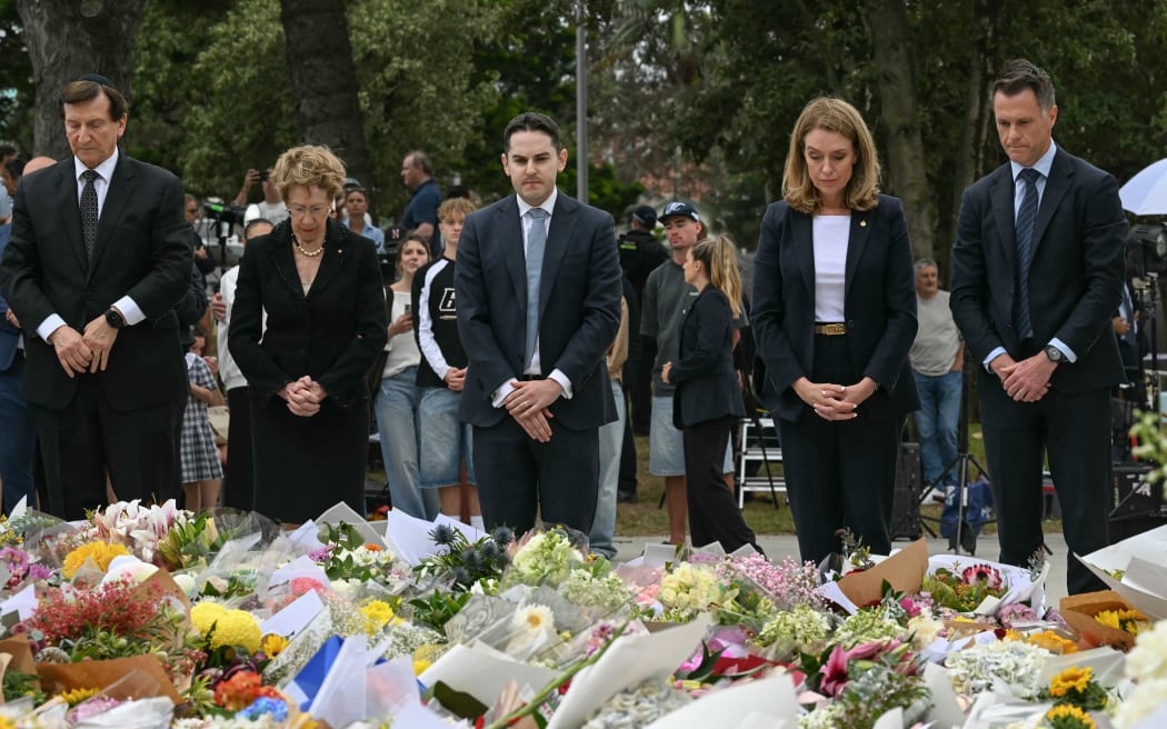 New South Wales Premier Chris Minns (R) and other dignitaries lay flowers as a tribute at the Bondi Pavillion in memory of the victims of a shooting at Bondi Beach, in Sydney on December 15, 2025. A father and son opened fire on a Jewish festival at Australia's Bondi Beach in a shooting spree that killed 15 people, including a child, authorities said on December 15, denouncing the attack as antisemitic "terrorism". (Photo by Saeed KHAN / AFP)