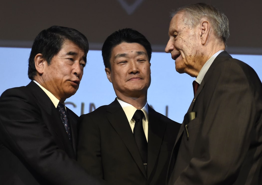 American World War II prisoner of war (POW) James Murphy (R) shakes hand with Hikaru Kimura (C), Mitsubishi Materials Corp. senior executive, and Yukio Okamoto.