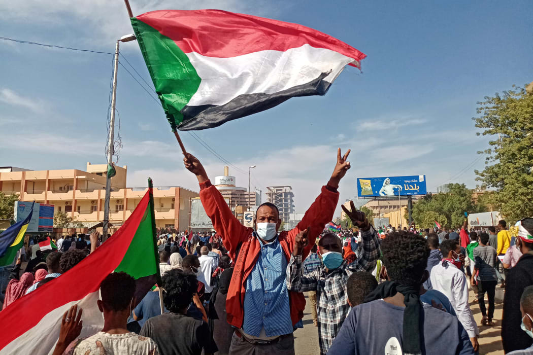 A Sudanese protester waves the national flag during a rally to mark three years since the start of mass demonstrations that led to the ouster of strongman Omar al-Bashir, in the capital Khartoum on December 19, 2021.
