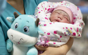 (210214) -- BEIJING, Feb. 14, 2021 (Xinhua) -- A baby born in the Year of the Ox is held by a health care worker at the maternity ward of Urumqi Maternal and Child Health Hospital in Urumqi, northwest China's Xinjiang Uygur Autonomous Region, Feb. 12, 2021.