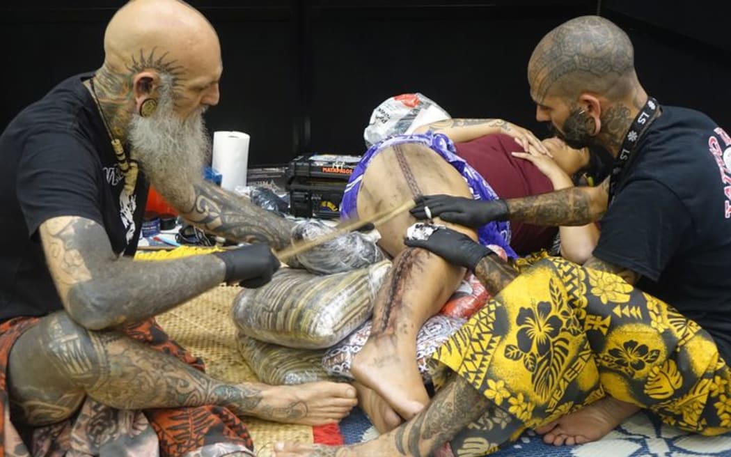 Former Auckland tattooist Brent McCown, (left) and his colleague Smiley Dogg, from Mallorca, create a tattoo using traditional Samoan techniques at the NZ Tattoo and Art Festival in New Plymouth.