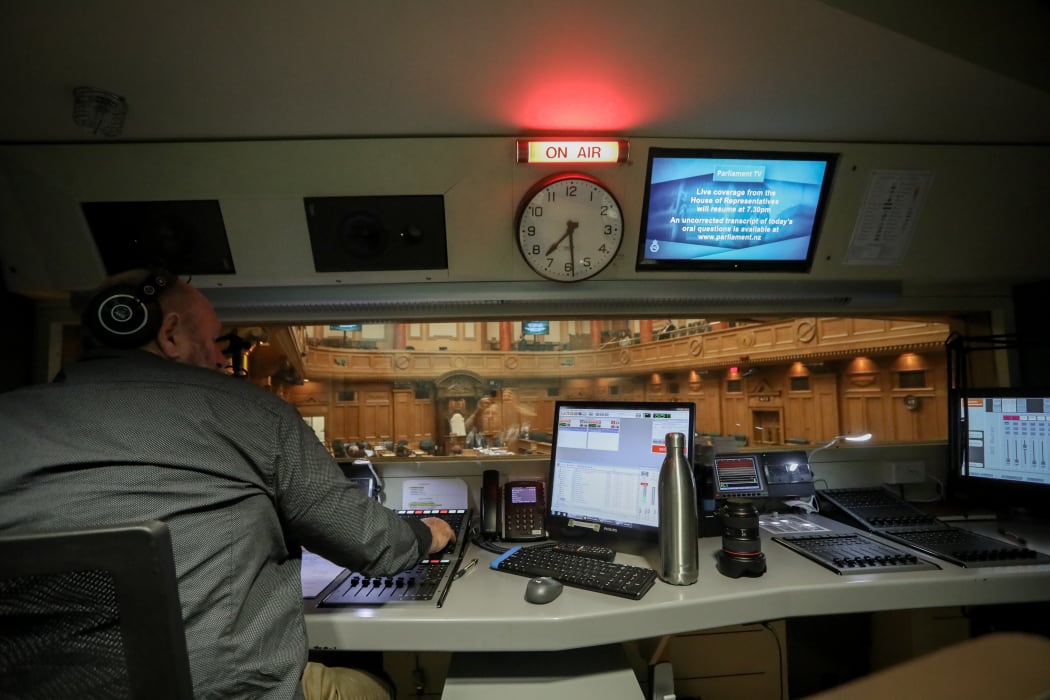 RNZ operator Colin Pearce leans into Parliament's evening sitting. In the audio booth he controls the debate audio for radio, TV and the chamber.